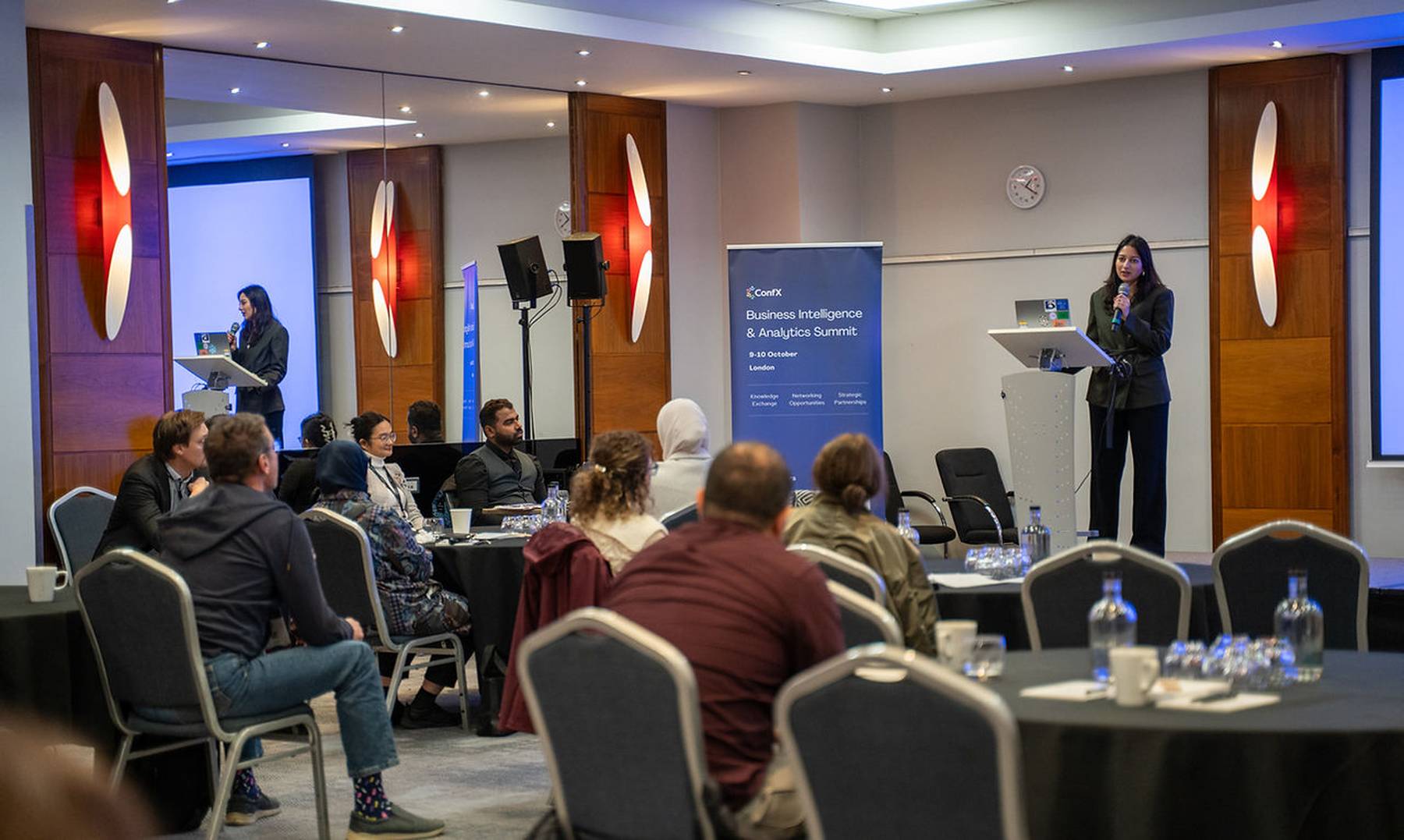 A speaker presenting to a seated audience at the ConfX Business Intelligence & Analytics Summit