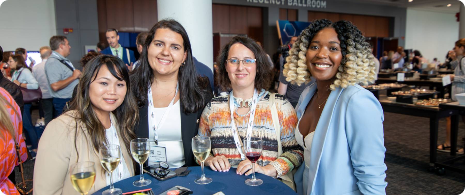 A group of women networking, enjoying drinks, smiling.